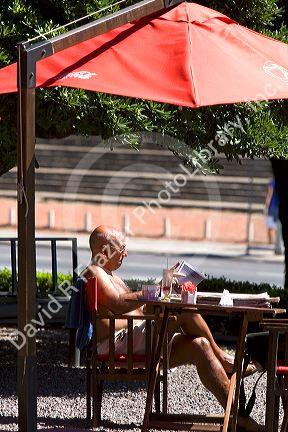 Man sitting at a outdoor cafe reading a magazine in Buenos Aires, Argentina.