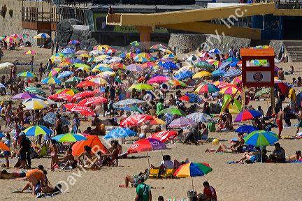 People sit under umbrellas for shade on the beach at Concon, Chile.