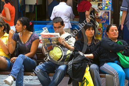 People sit on a bench on the Paseo Ahumada in Santiago, Chile.