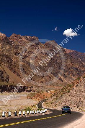 Auto driving on a highway along the Mendoza River in the Andes Mountain Range west of Upsallata, Argentina.
