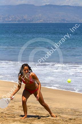 Woman playing paddle ball on the beach at Renaca on the Pacific Ocean in Chile.