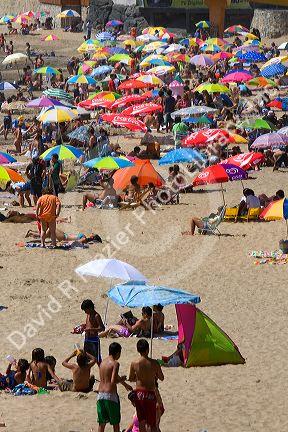People sit under umbrellas for shade on the beach at Concon, Chile.