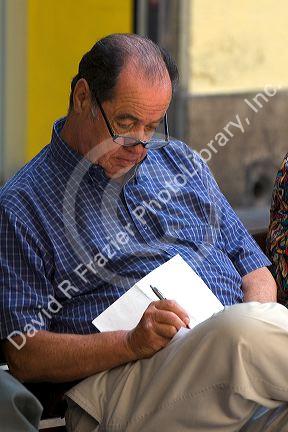Man writing on a peice of paper in Santiago, Chile.