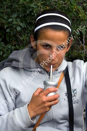 Argentine woman drinking mate at the Perito Moreno Glacier in Patagonia, Argentina.