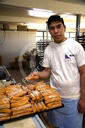 Baker with a tray of churros at the Panaderia Union, Tierra del Fuego, Argentina.