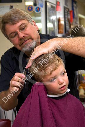 Barber giving a three year old boy a haircut in Tampa, Florida. MR