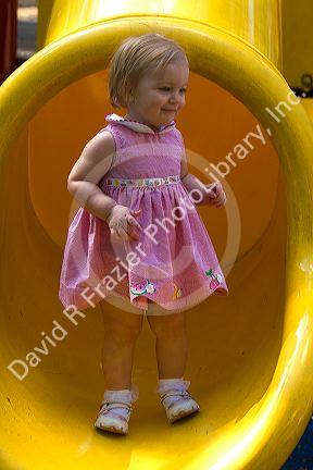 15 month old girl standing at the end of a slide in Tampa, Florida. MR