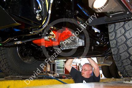 Worker looks under a newly manufactured fire truck chassis at Spartan Motors in Charlotte, Michigan.