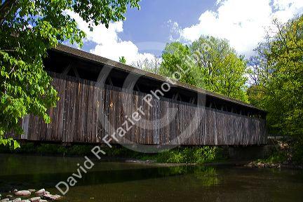 Whites Bridge, a brown truss covered bridge spanning the Flat River in Keene Township, Michigan.