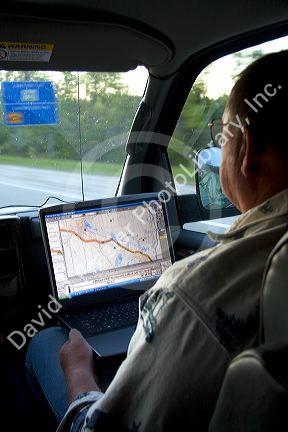 Passenger in a moving vehicle using GPS navigation on a laptop in Michigan. MR