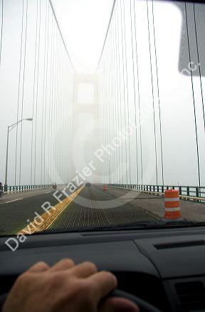View from the inside of a car crossing the Mackinac Bridge on a foggy day in Michigan.