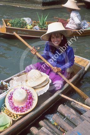 Woman selling hats from a boat at the Floating Market near Bangkok, Thailand.
