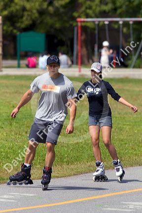 Couple inline skating along the Seawall path in Stanley Park at Vancouver, British Columbia, Canada.