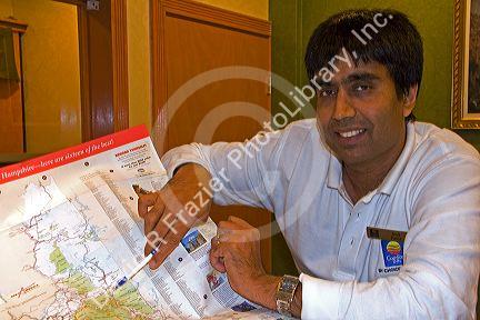 Hotel desk clerk giving directions using a map in the town of Ashland, New Hampshire, USA.