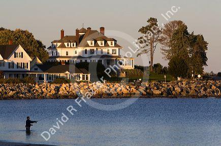 Waterfront home and man fishing at the village of Hampton Beach, New Hampshire, USA.