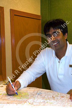 Hotel desk clerk using a map to give directions in the town of Ashland, New Hampshire, USA.
