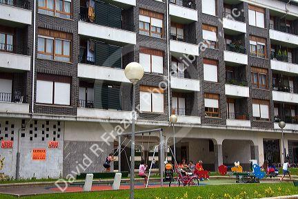 Children use playground equipment in front of an apartment housing unit in Guernica in the province of Biscay, Basque Country, Northern Spain.