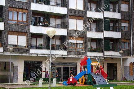 Children use playground equipment in front of an apartment housing unit in Guernica in the province of Biscay, Basque Country, Northern Spain.
