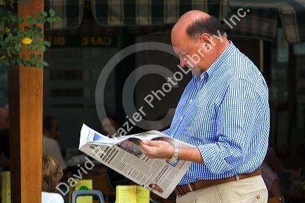 Man reading the newspaper in the town of Llanes, Asturias, Spain.