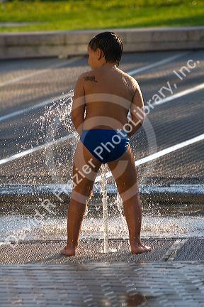 Boy playing in a fountain at the Guggenheim Museum in the city of Bilbao, Biscay, Basque Country, northern Spain.