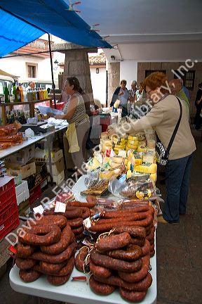 Vendor selling cheese and meats at an outdoor market in the town of Cangas de Onis, Asturias, northern Spain.