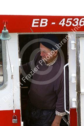 Commercial fisherman on his boat in the harbor at Llanes, Asturias, Spain.