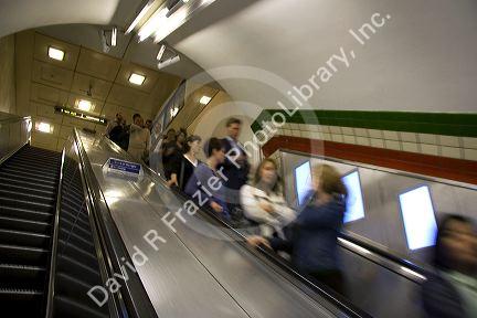 People ride an escalator in the London Underground transit system in London, England.
