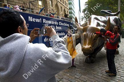 People having their photo taken with the Wall Street Bull in Bowling Green park near Wall Street, New York City, New York, USA.