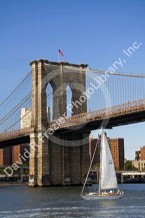 Sailboat passing below the Brooklyn Bridge in New York City, New York, USA.