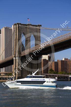 Seastreak power boat passing below the Brooklyn Bridge in New York City, New York, USA.