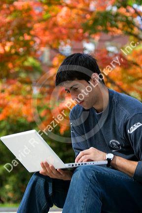 Male student studying with a laptop computer in Harvard Yard at Harvard University in Cambridge, Greater Boston, Massachusetts, USA. MR