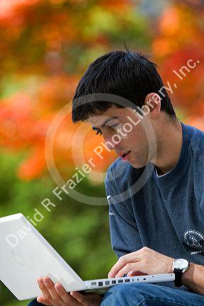 Male student studying with a laptop computer in Harvard Yard at Harvard University in Cambridge, Greater Boston, Massachusetts, USA. MR