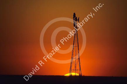 Silhouetted windmill at sunset on farmland in western Kansas.