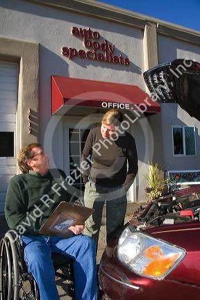 Handicapped insurance claims adjuster with customer assessing the damage of her automobile in Boise, Idaho, USA. MR