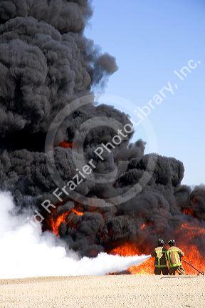 Firefighters using fire retardant foam to put out a jet fuel fire at an airport training facility in Boise, Idaho, USA.