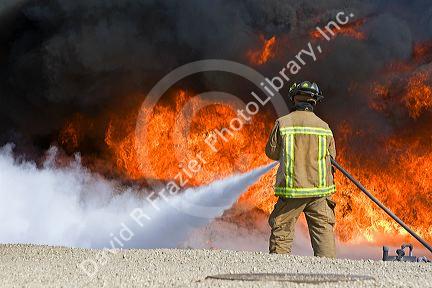 Firefighter using fire retardant foam to put out a jet fuel fire at an airport training facility in Boise, Idaho, USA.