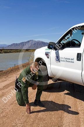 United States Border Patrol agent checking for footprints at the U.S./Mexico border along the All American Canal near Calexico, California.