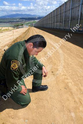 United States Border Patrol agent checking for footprints at the U.S./Mexico border near San Diego, California.