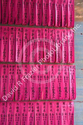 Prayers written in Chinese characters on pink paper displayed at the Quan Am Pagoda, a famous Chinese temple in the Cholon district of Ho Chi Minh City, Vietnam.