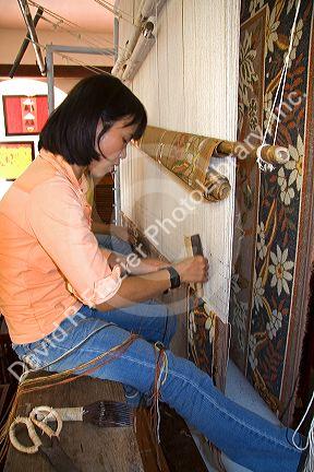 Vietnamese woman manufacturing woven rugs at a craft center in Hoi An, Vietnam.