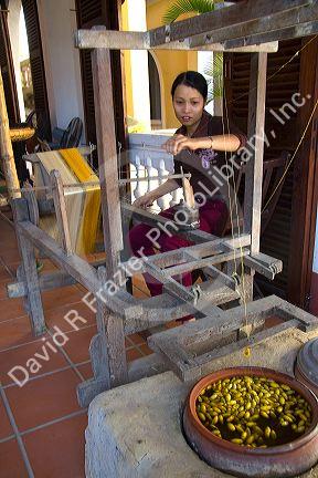 Vietnamese woman spinning silk from the silkworm cocoon in Hoi An, Vietnam.