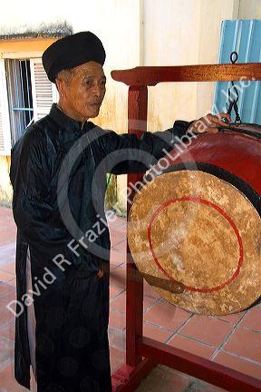 Monk sounding a drum at a temple in Hoi An, Vietnam.