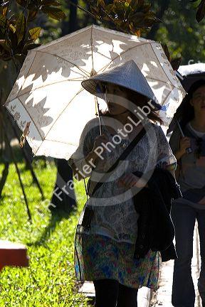 Vietnamese woman walking with an umbrella at the Imperial Citadel of Hue, Vietnam.