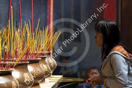 Vietnamese woman burning incense at the Quan Am Pagoda, a famous Chinese temple in the Cholon district of Ho Chi Minh City, Vietnam.
