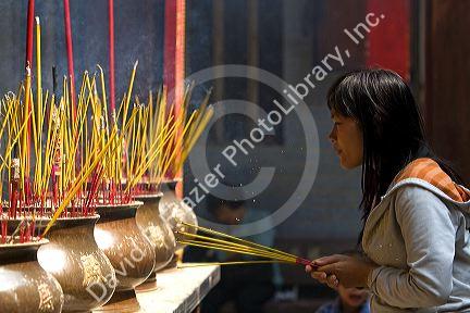 Vietnamese woman burning incense at the Quan Am Pagoda, a famous Chinese temple in the Cholon district of Ho Chi Minh City, Vietnam.