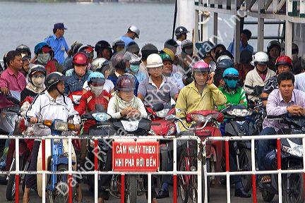Passengers on motorbikes ride a ferry across the Saigon River in Ho Chi Minh City, Vietnam.