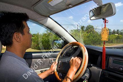 Driver with Buddhist pendant hanging from mirror in Ho Chi Minh City, Vietnam.