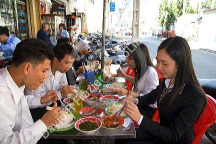 Vietnamese office workers eat lunch at a sidewalk cafe in Ho Chi Minh City, Vietnam.