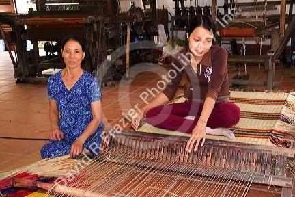 Vietnamese women weaving mats at a craft factory in Hoi An, Vietnam.