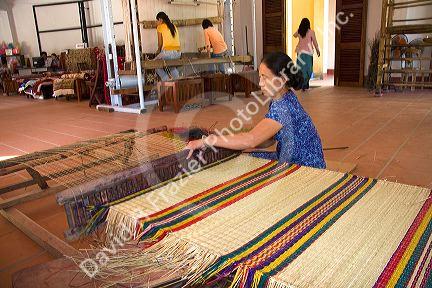 Vietnamese woman manufacturing woven rugs at a craft center in Hoi An, Vietnam.